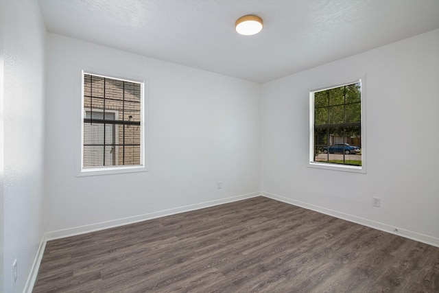 spare room with dark wood finished floors and baseboards