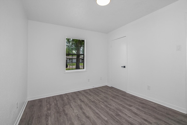 unfurnished room with dark wood-style flooring and baseboards