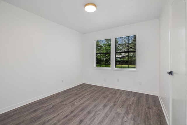 unfurnished room featuring baseboards and dark wood-type flooring