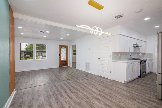 kitchen featuring visible vents, stainless steel range with gas stovetop, wood finished floors, and light countertops
