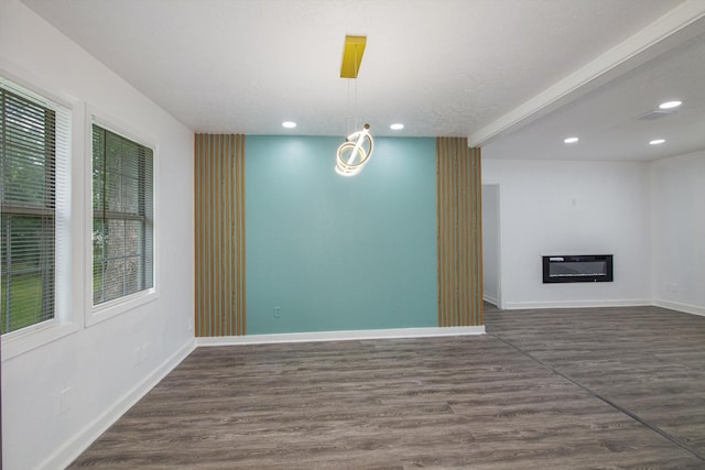 spare room with baseboards, recessed lighting, dark wood-type flooring, and a glass covered fireplace