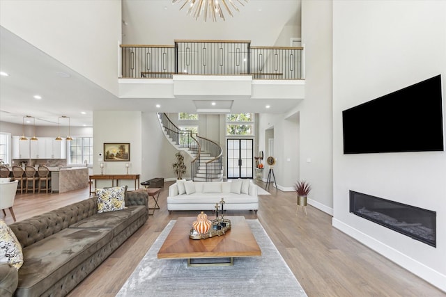 13927 Perthshire Rd, Houston, TX 77079 - living room with stairway, baseboards, wood finished floors, a towering ceiling, and recessed lighting
