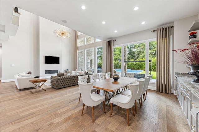 13927 Perthshire Rd, Houston, TX 77079 - dining room with recessed lighting, light wood finished floors, a high ceiling, baseboards, and a glass covered fireplace