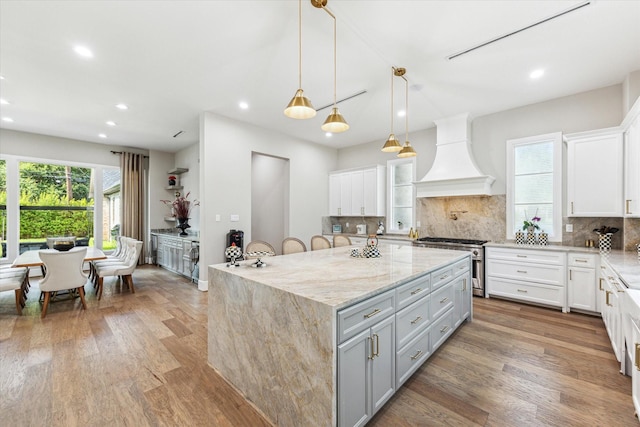13927 Perthshire Rd, Houston, TX 77079 - kitchen with high end stove, custom range hood, gray cabinets, a center island, and wood finished floors