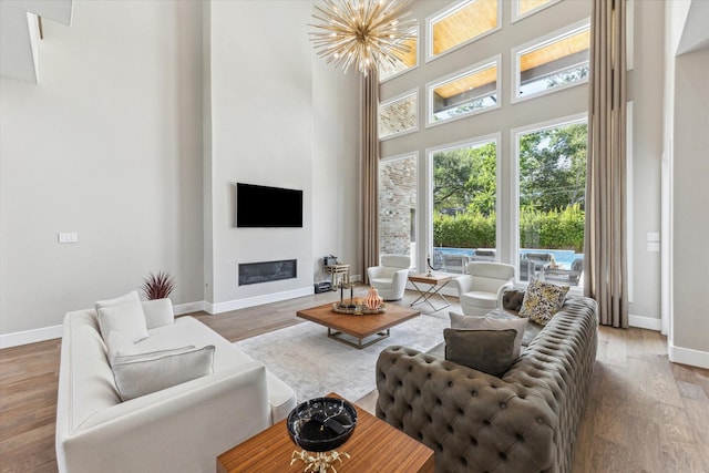 13927 Perthshire Rd, Houston, TX 77079 - living room featuring baseboards, a high ceiling, wood finished floors, a glass covered fireplace, and a chandelier