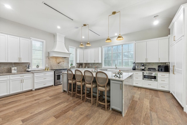 13927 Perthshire Rd, Houston, TX 77079 - kitchen featuring high end range, a sink, decorative backsplash, a breakfast bar, and premium range hood