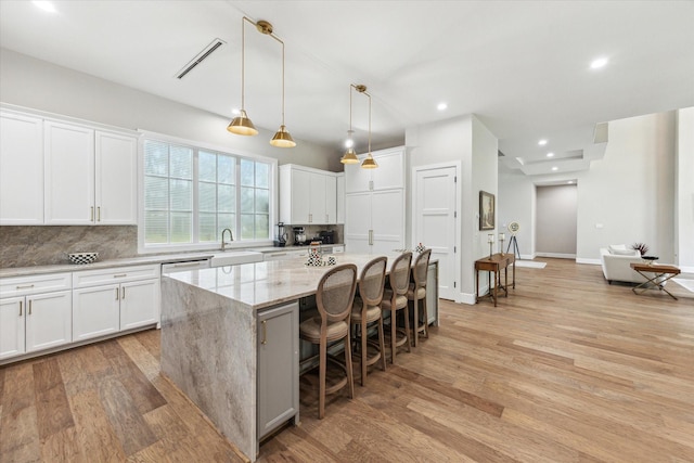 13927 Perthshire Rd, Houston, TX 77079 - kitchen featuring a kitchen island, decorative backsplash, light wood-style floors, white cabinets, and recessed lighting