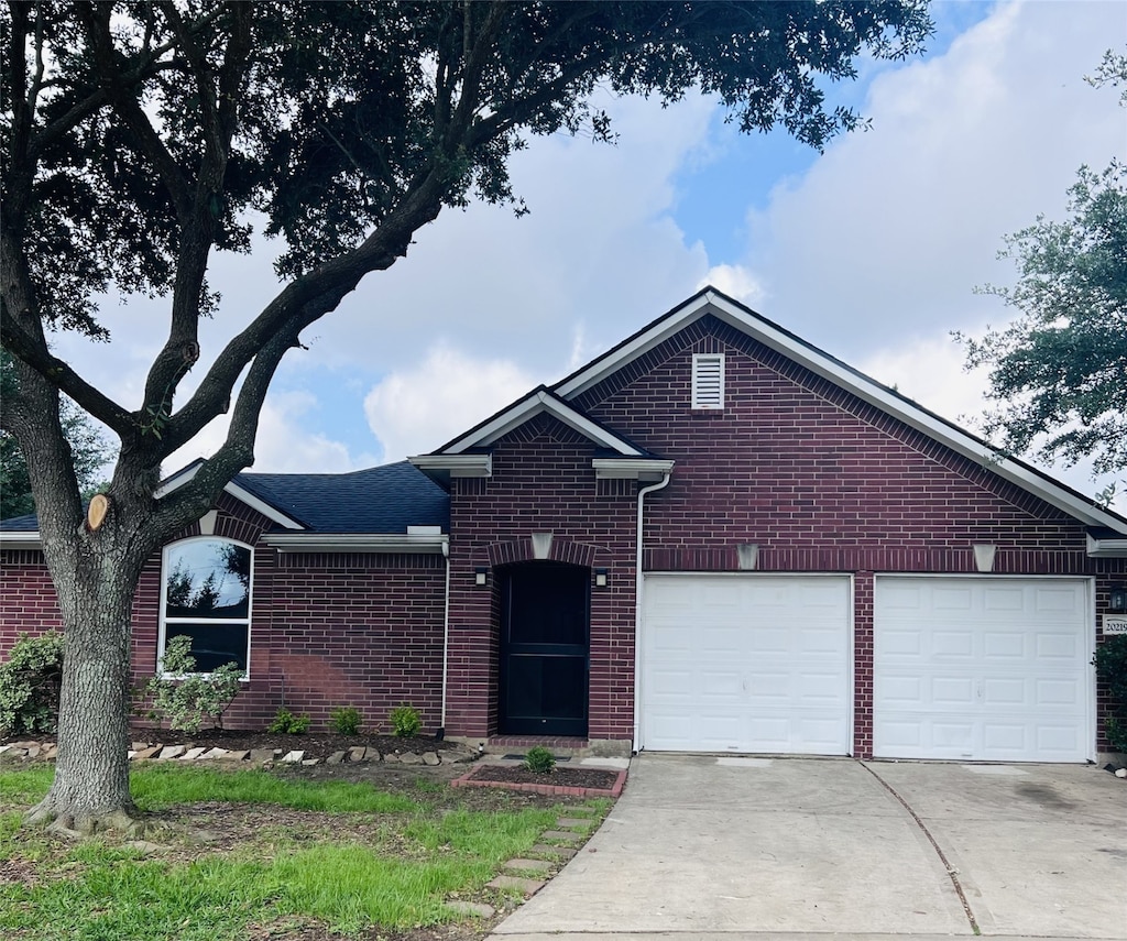 20219 Plum Trails Ct, Katy, TX 77449 - view of front of home featuring driveway, roof with shingles, an attached garage, and brick siding