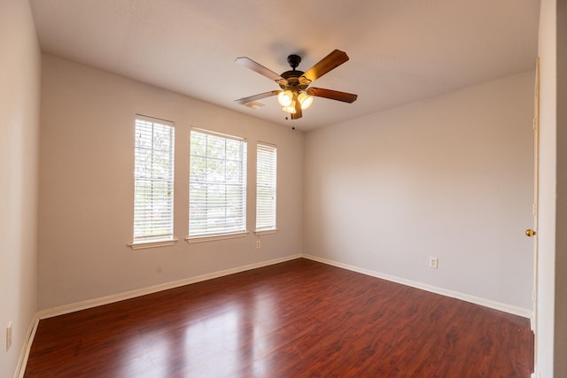 spare room featuring dark wood-style flooring, ceiling fan, and baseboards