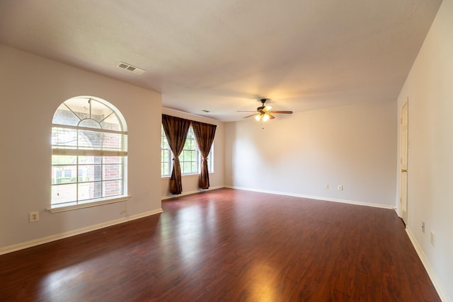 unfurnished room with visible vents, dark wood finished floors, ceiling fan, and baseboards