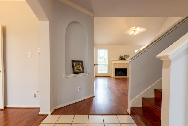foyer with a tiled fireplace, arched walkways, wood finished floors, and stairway