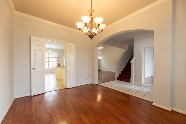 unfurnished dining area featuring an inviting chandelier, arched walkways, wood finished floors, and ornamental molding