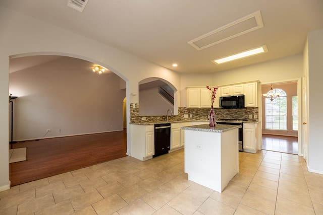 kitchen featuring decorative backsplash, a kitchen island, visible vents, white cabinets, and black appliances