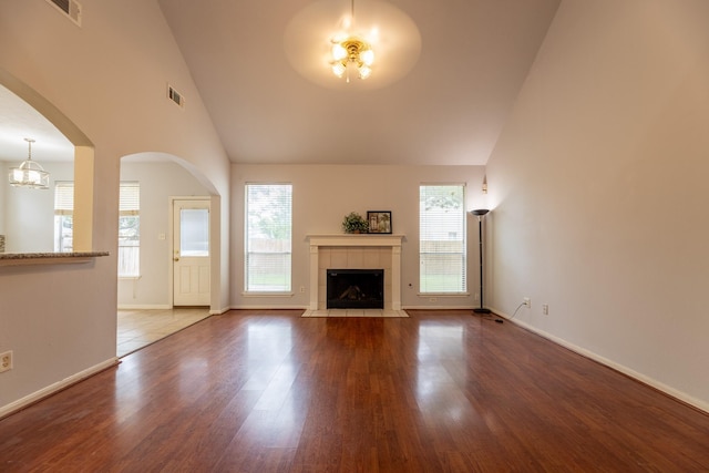 unfurnished living room featuring a tiled fireplace, baseboards, wood finished floors, and visible vents