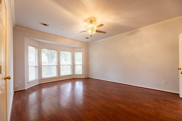 spare room featuring a ceiling fan, visible vents, dark wood finished floors, baseboards, and ornamental molding
