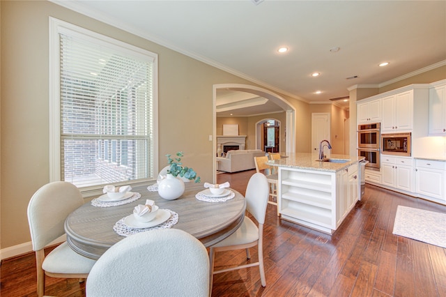 dining area with arched walkways, baseboards, dark wood-style floors, ornamental molding, and recessed lighting