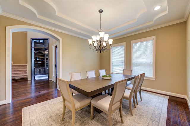 dining room with arched walkways, ornamental molding, a tray ceiling, and a notable chandelier