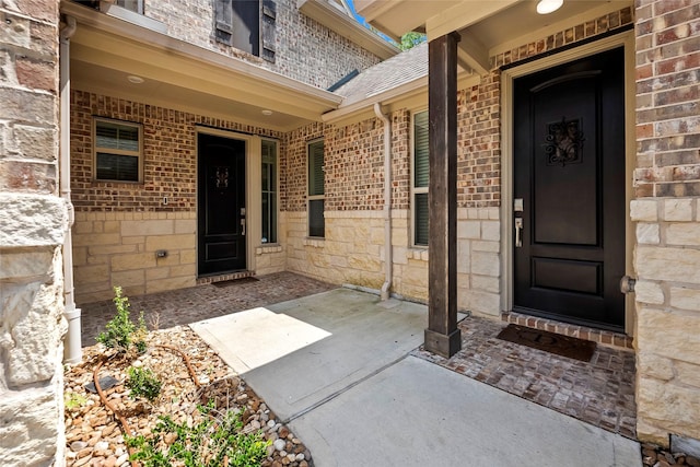view of exterior entry with stone siding and brick siding