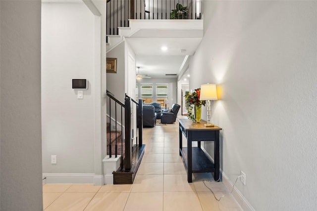 corridor with light tile patterned floors, stairs, and baseboards