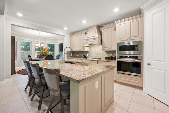 kitchen featuring a sink, stainless steel appliances, cream cabinetry, light tile patterned flooring, and custom exhaust hood