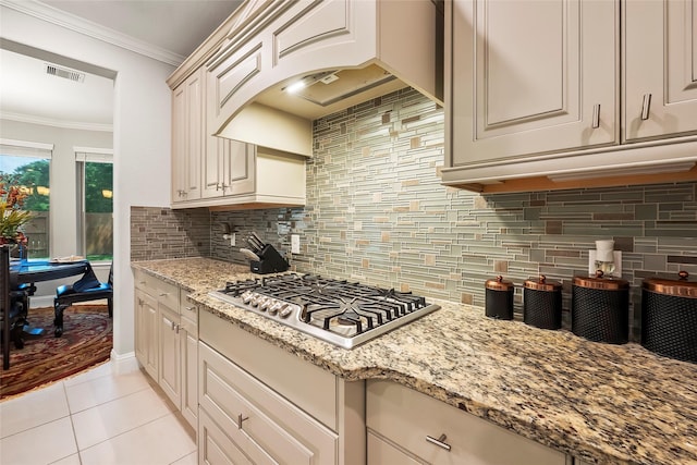 kitchen with light stone counters, crown molding, custom range hood, light tile patterned flooring, and stainless steel gas cooktop