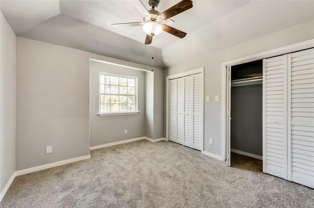 unfurnished bedroom featuring lofted ceiling, multiple closets, baseboards, and carpet floors