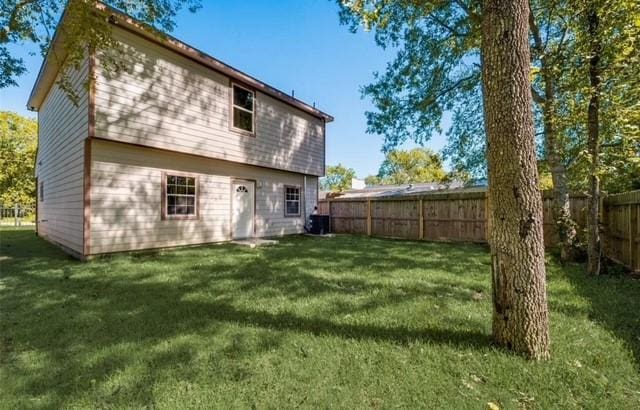 back of house with a fenced backyard and a yard
