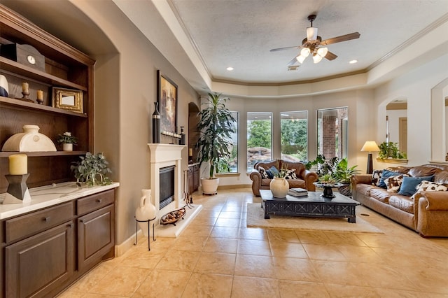 6310 Indiangrass Ct, Katy, TX 77494 - living area with ornamental molding, a ceiling fan, light tile patterned floors, a tray ceiling, and a glass covered fireplace