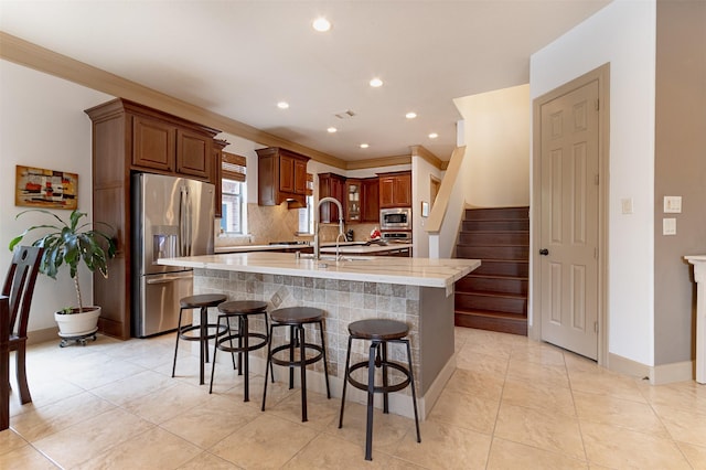 6310 Indiangrass Ct, Katy, TX 77494 - kitchen with a breakfast bar, a center island with sink, recessed lighting, decorative backsplash, and appliances with stainless steel finishes