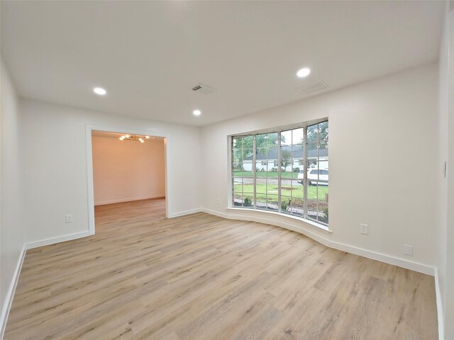 spare room with recessed lighting, an inviting chandelier, light wood-style flooring, baseboards, and visible vents