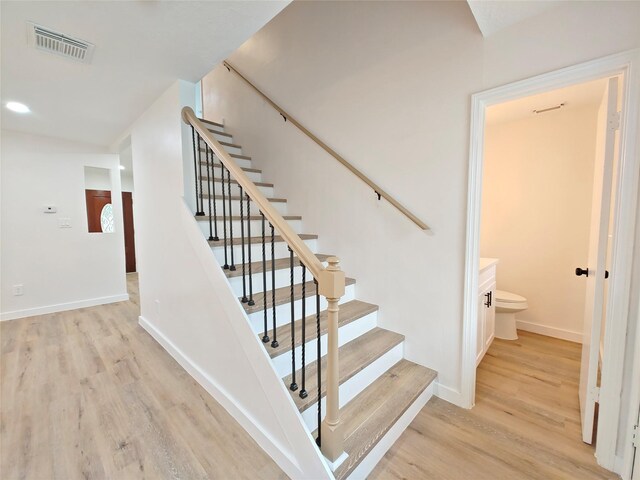 stairway with visible vents, wood finished floors, and baseboards