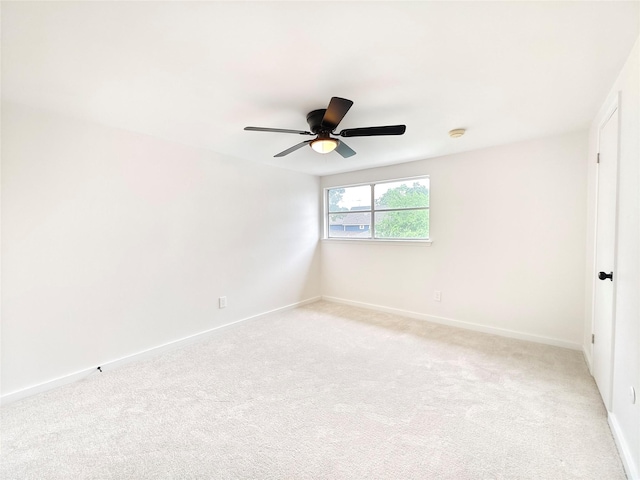 spare room with light colored carpet, ceiling fan, and baseboards