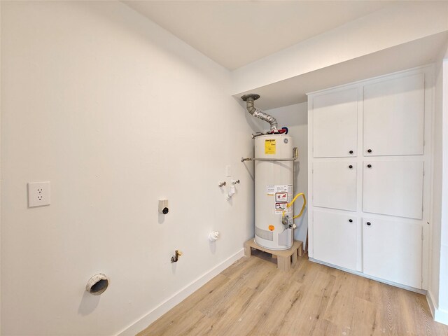 clothes washing area with strapped water heater, laundry area, light wood-style flooring, baseboards, and gas dryer hookup