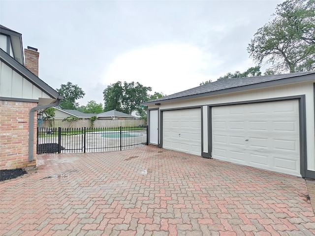 garage with fence and decorative driveway