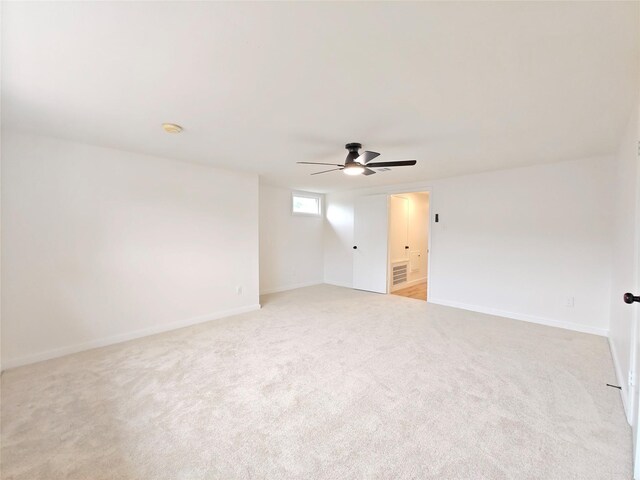 unfurnished room with a ceiling fan, visible vents, light carpet, and baseboards