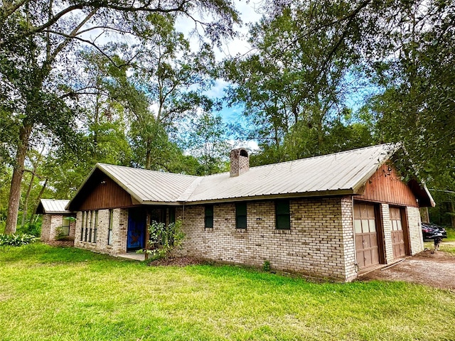 360 Evangeline Dr, Vidor, TX 77662 - rear view of house featuring a chimney, brick siding, metal roof, a garage, and a lawn