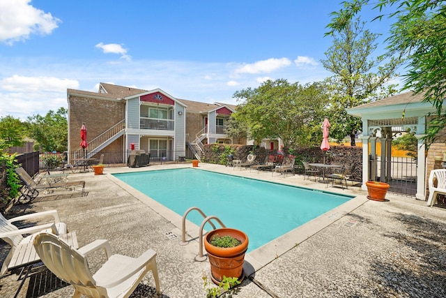 community pool with fence, stairs, and a patio area