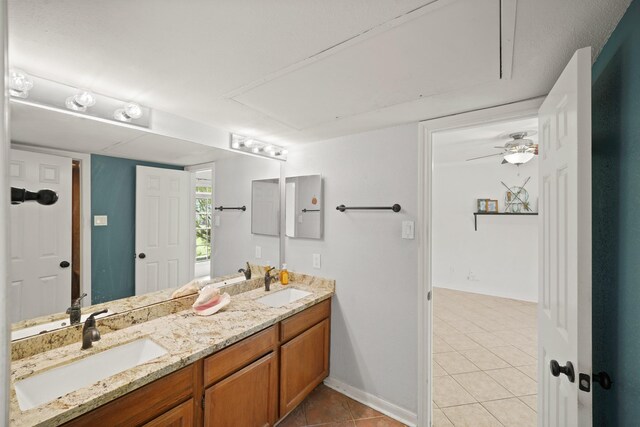 bathroom featuring double vanity, baseboards, a sink, and tile patterned flooring