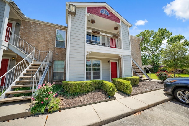 view of property featuring stairway and brick siding
