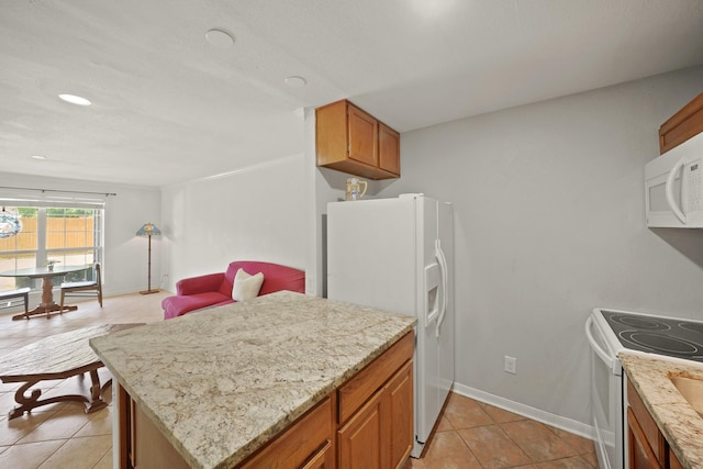 kitchen featuring brown cabinets, light stone counters, white appliances, baseboards, and light tile patterned floors