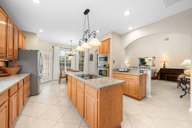 kitchen with light stone countertops, appliances with stainless steel finishes, light tile patterned floors, and a center island