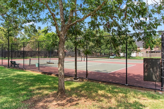 view of tennis court featuring a lawn and fence
