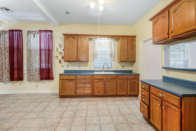 kitchen featuring visible vents, a sink, brown cabinetry, and dark countertops