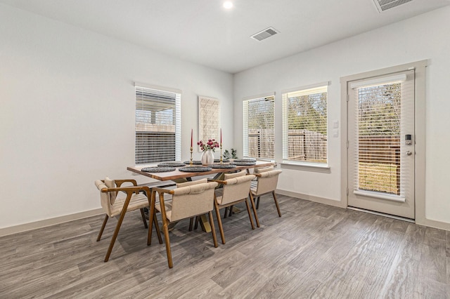 dining space with light wood-style floors, plenty of natural light, and visible vents