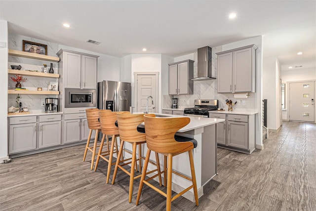 12823 Tokenhouse Ln, Houston, TX 77047 - kitchen featuring gray cabinets, appliances with stainless steel finishes, wall chimney exhaust hood, decorative backsplash, and light countertops