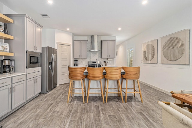 kitchen featuring visible vents, open shelves, gray cabinetry, stainless steel appliances, and wall chimney exhaust hood