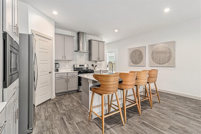 12823 Tokenhouse Ln, Houston, TX 77047 - kitchen featuring gray cabinets, stainless steel appliances, wall chimney exhaust hood, wood finished floors, and recessed lighting