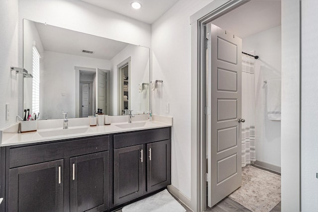 bathroom with a shower with shower curtain, double vanity, visible vents, and a sink