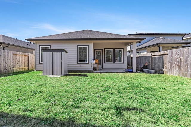 back of property with a lawn, an outbuilding, a fenced backyard, a storage unit, and a patio