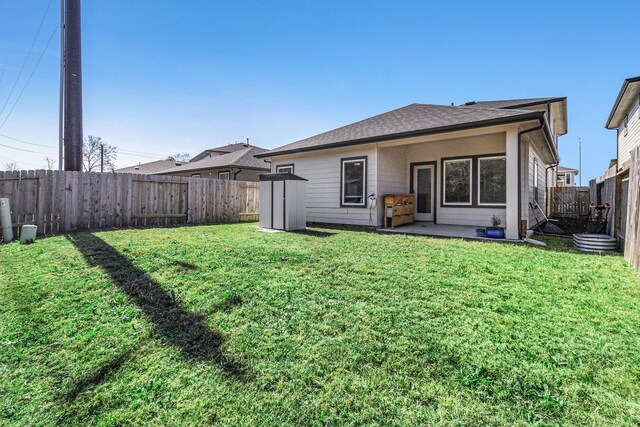 back of property with a yard, a patio, a shingled roof, and a fenced backyard